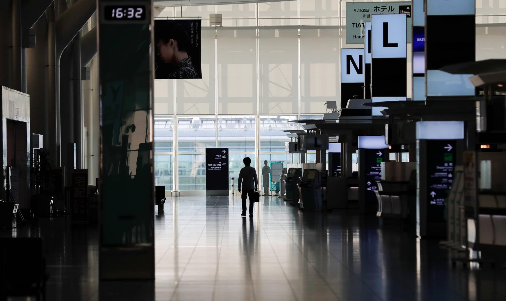 A person stands in an almost empty terminal of Tokyo's Haneda Airport in late April. Starting Tuesday, Japan is set to lift its entry restrictions on foreign residents, allowing those who left before the strict coro<em></em>navirus curbs were imposed to return, and those planning to leave temporarily to proceed without fear of being locked out. | REUTERS