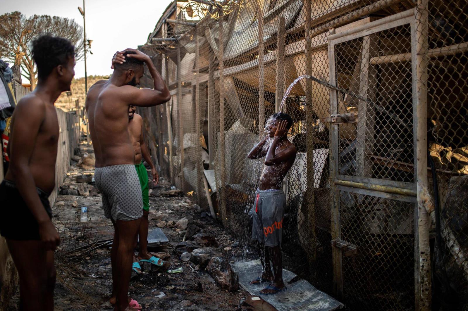 Migrants shower in the burnt camp of Moria on the Greek Aegean island of Lesbos on Wednesday after a major fire broke out. | AFP-JIJI