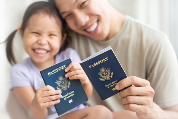 Asian dad and daughter holding amercian passports with pride. Immigration citizenship